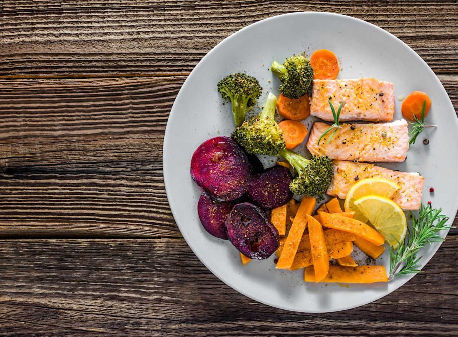 Gourmet dish with cooked vegetables, grilled salmon and fries. Dinner on plate, top view